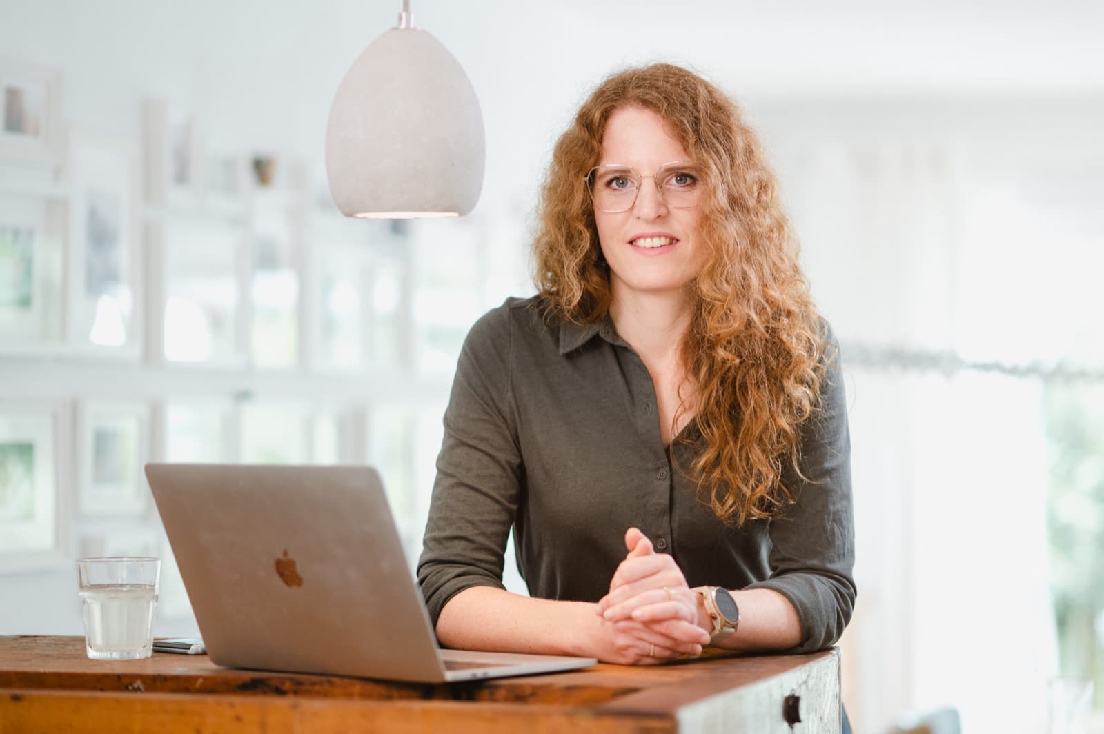 Lisa Engel steht entspannt am Laptop und lächelt in die Kamera