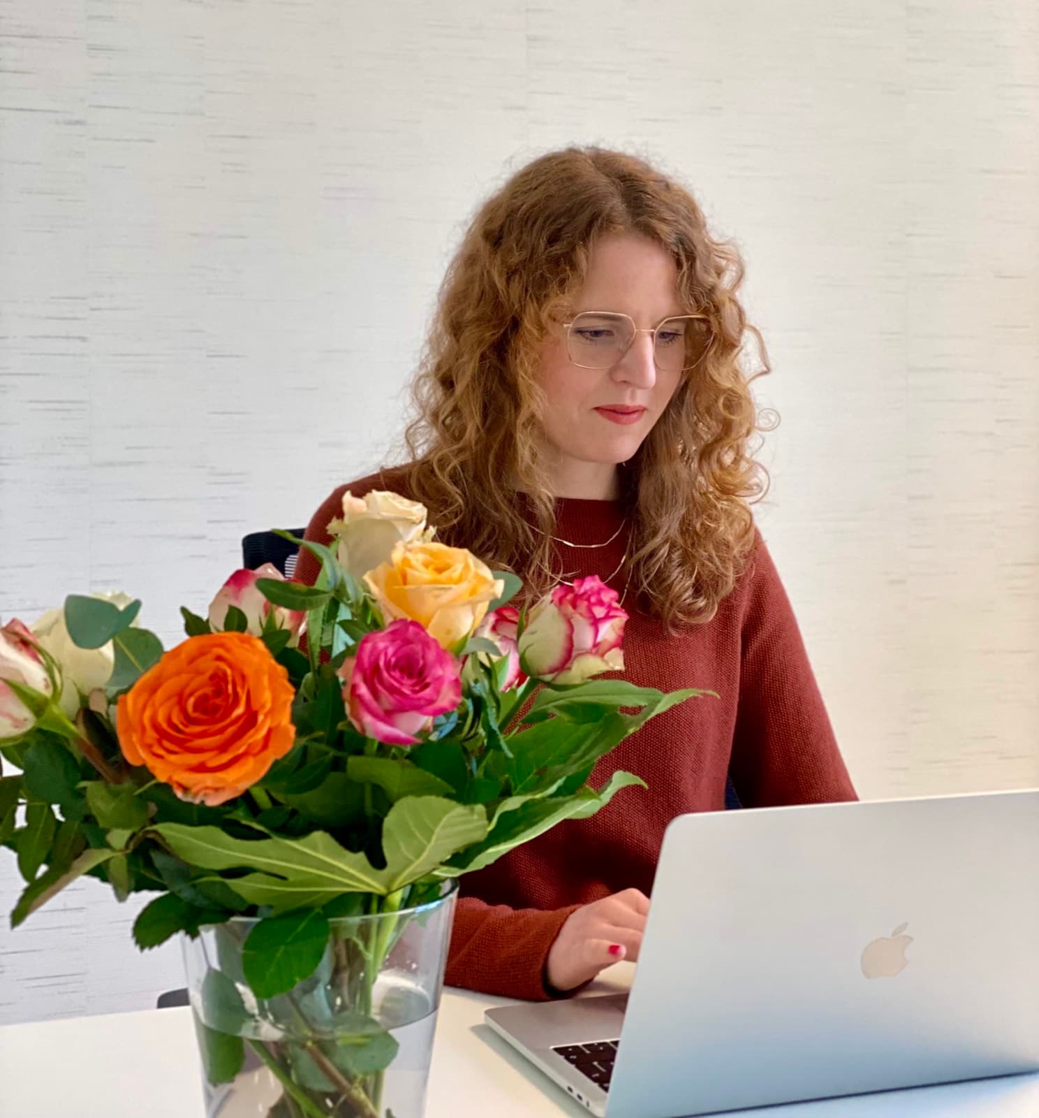 Lisa Engel arbeitet konzentriert am Laptop, davor ein bunter Rosenstrauß